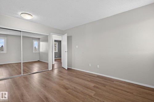 Spacious room featuring wood-finish flooring, light grey painted walls, and a ceiling-mounted light fixture - 18 17409 95 Street, Edmonton, AB - Indoor Photo Showing Other Room