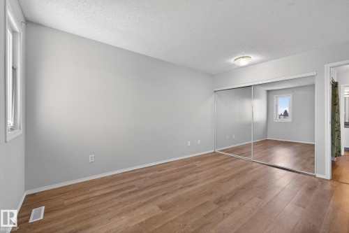 Room featuring wood-finish flooring, light grey painted walls, and white baseboards - 18 17409 95 Street, Edmonton, AB - Indoor Photo Showing Other Room