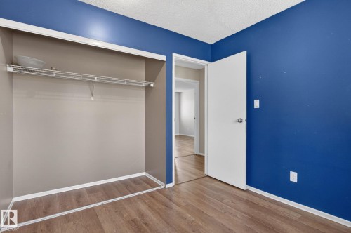 Room with wood-finish flooring, a vibrant blue accent wall, and white trim - 18 17409 95 Street, Edmonton, AB - Indoor