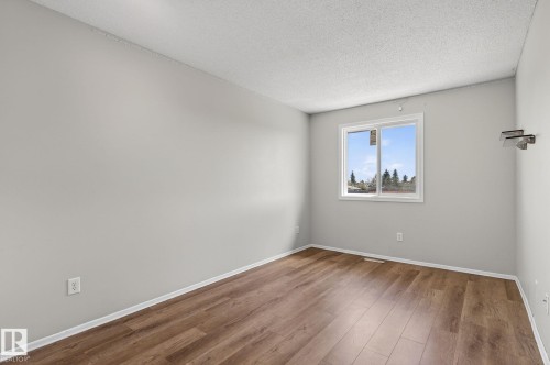 Bright room featuring wood-finish flooring, light grey painted walls, a white trim package, and a window with white casing - 18 17409 95 Street, Edmonton, AB - Indoor Photo Showing Other Room