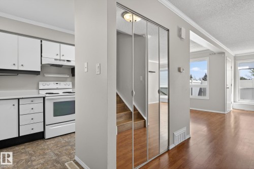 Entryway featuring mirrored closet doors, wood-finish flooring, and a stairway with wood treads - 18 17409 95 Street, Edmonton, AB - Indoor Photo Showing Kitchen