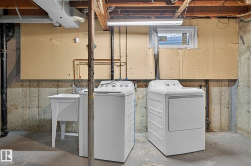 Basement laundry area featuring a utility sink with a chrome faucet, exposed ceiling joists, and a perimeter concrete wall - 18 17409 95 Street, Edmonton, AB - Indoor Photo Showing Laundry Room