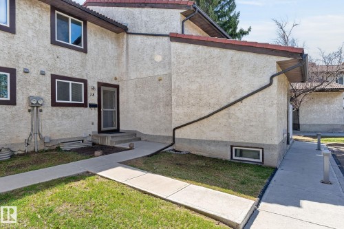 Stucco exterior featuring multiple windows with dark trim - 18 17409 95 Street, Edmonton, AB - Outdoor