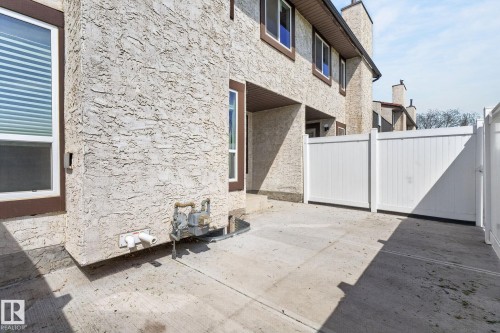 Private concrete patio featuring a white vinyl fence and stucco exterior - 18 17409 95 Street, Edmonton, AB - Outdoor With Exterior