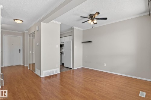 Spacious living area featuring wood-finish flooring, light gray walls, and white crown molding - 18 17409 95 Street, Edmonton, AB - Indoor Photo Showing Other Room