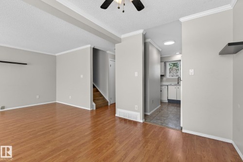 Spacious room featuring wood-finish flooring, light grey painted walls, white crown molding, and a ceiling fan with integrated lighting - 18 17409 95 Street, Edmonton, AB - Indoor Photo Showing Other Room