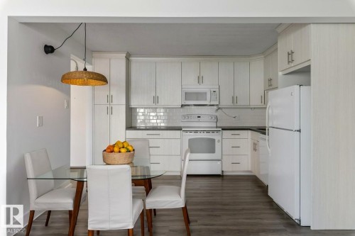 Updated Kitchen and dining area featuring amble  cabinetry, subway tile backsplash & full size appliances, including a dishwasher, fridge, stove & microwave hood fan. - 101 8604 Gateway Boulevard, Edmonton, AB - Indoor Photo Showing Kitchen