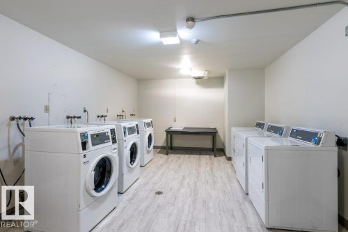 Dedicated laundry facility featuring multiple washing machines, dryers & a utility sink. - 101 8604 Gateway Boulevard, Edmonton, AB - Indoor Photo Showing Laundry Room