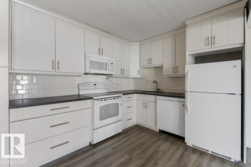 Updated Kitchen and dining area featuring amble  cabinetry, subway tile backsplash & full size appliances, including a dishwasher, fridge, stove & microwave hood fan. - 101 8604 Gateway Boulevard, Edmonton, AB - Indoor Photo Showing Kitchen