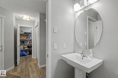 Pedestal sink with an oval mirror and contemporary vanity lighting - 1211 29 Street, Edmonton, AB - Indoor Photo Showing Bathroom