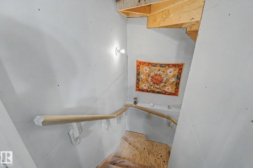 Stairwell featuring unfinished drywall, exposed wood framing, and a wooden handrail - 1211 29 Street, Edmonton, AB - Indoor Photo Showing Other Room