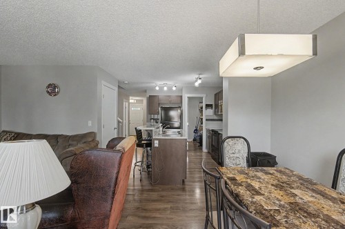 Open-concept living space featuring wood-finish flooring, a kitchen island with seating, dark wood cabinetry, and a contemporary rectangular pendant light fixture - 1211 29 Street, Edmonton, AB - Indoor Photo Showing Dining Room