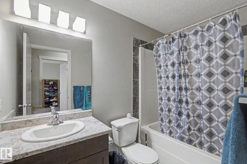 Bathroom featuring a built-in vanity with a composite countertop and integrated sink, a large wall-mounted mirror, and a full-size bathtub with a shower enclosure - 1211 29 Street, Edmonton, AB - Indoor Photo Showing Bathroom