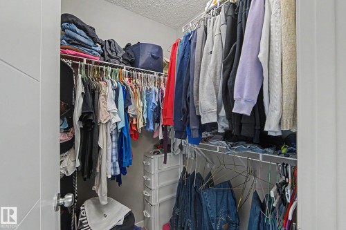 Walk-in closet featuring wire shelving, multiple hanging rods, and a textured ceiling - 1211 29 Street, Edmonton, AB - Indoor With Storage