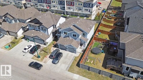 Two-story property featuring light blue siding with white trim, a double attached garage, and a fenced backyard with a raised wooden deck - 1211 29 Street, Edmonton, AB - Outdoor