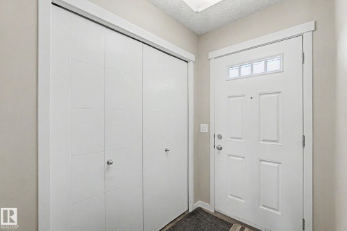 Entryway featuring a paneled front door with transom windows, wood-finish flooring, and a double bi-fold closet with contemporary hardware - 1211 29 Street, Edmonton, AB - Indoor Photo Showing Other Room