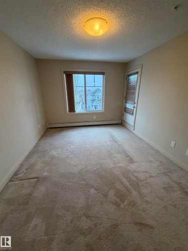 Living space with neutral-toned walls, carpet flooring, a window providing natural light, and a ceiling-mounted light fixture - 313 6084 Stanton Drive, Edmonton, AB - Indoor Photo Showing Other Room