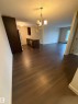 This living area features rich dark flooring, a contemporary chandelier, and a window providing natural light - 313 6084 Stanton Drive, Edmonton, AB  - Indoor Photo Showing Other Room 