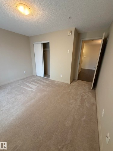 The room features neutral-toned carpet flooring and light-colored walls, complemented by a ceiling-mounted light fixture - 313 6084 Stanton Drive, Edmonton, AB - Indoor Photo Showing Other Room