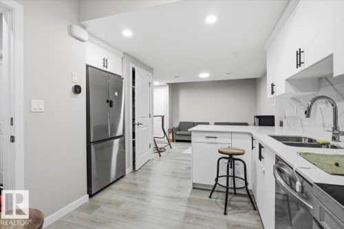 Contemporary kitchen featuring white cabinetry, a stainless steel refrigerator, and a coordinating dishwasher - 7056 182 Avenue, Edmonton, AB - Indoor Photo Showing Kitchen With Double Sink