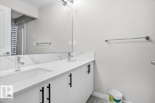 Modern bathroom featuring a double vanity with integrated sinks, white countertops, and a full-width mirror - 7056 182 Avenue, Edmonton, AB - Indoor Photo Showing Bathroom