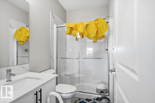 Bathroom featuring a shower with glass enclosure, white vanity with quartz-finish countertop, undermount sink, and chrome faucet - 7056 182 Avenue, Edmonton, AB - Indoor Photo Showing Bathroom