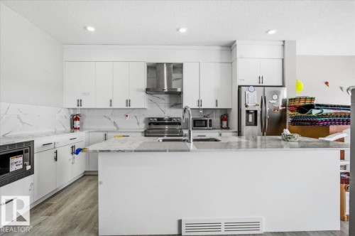 Modern kitchen featuring light wood-finish flooring and white cabinetry - 7056 182 Avenue, Edmonton, AB - Indoor Photo Showing Kitchen With Double Sink
