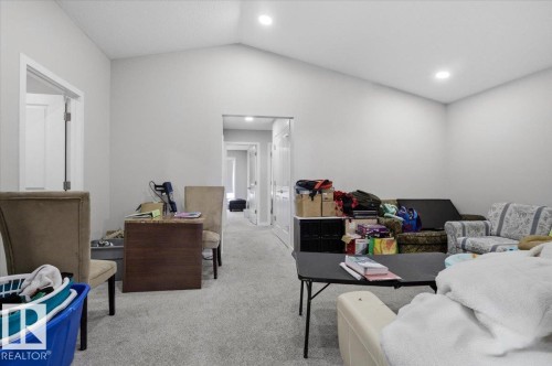 Spacious room featuring vaulted ceilings, recessed lighting, neutral wall paint, and light-toned carpet flooring - 7056 182 Avenue, Edmonton, AB - Indoor
