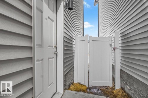 White paneled entry door with silver hardware, complemented by light gray horizontal siding - 7056 182 Avenue, Edmonton, AB -  With Exterior
