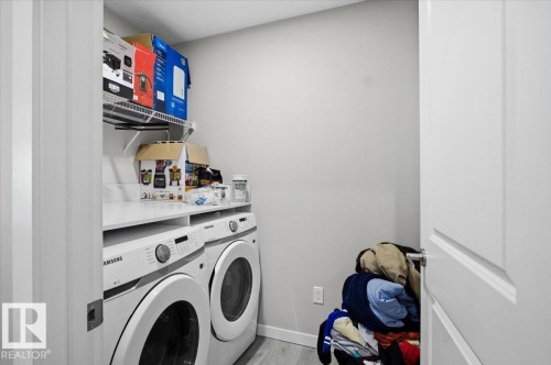 Dedicated laundry area featuring a white front-loading washer and dryer set, white countertop, and upper wire shelving - 7056 182 Avenue, Edmonton, AB - Indoor Photo Showing Laundry Room