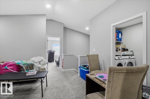 Carpeted loft area featuring a laundry closet with stacked appliances and integrated shelving - 7056 182 Avenue, Edmonton, AB - Indoor