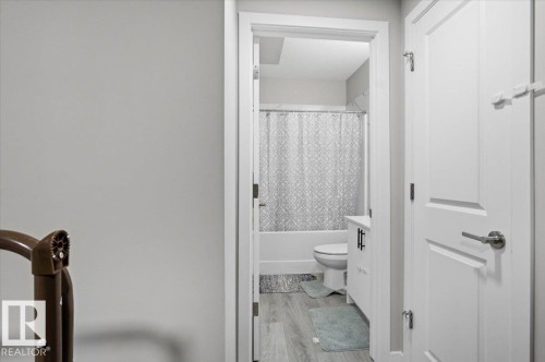 Bathroom featuring a white vanity with black hardware, a toilet, and a tub with a patterned shower curtain - 7056 182 Avenue, Edmonton, AB - Indoor Photo Showing Bathroom