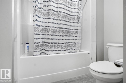 White tub and shower combination with a single handle fixture and light-colored wall tile - 7056 182 Avenue, Edmonton, AB - Indoor Photo Showing Bathroom