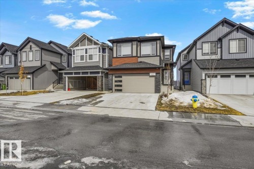 Contemporary two-story home featuring a two-car garage with horizontal paneling, stone accents, and a mixed material facade - 7056 182 Avenue, Edmonton, AB - Outdoor With Facade