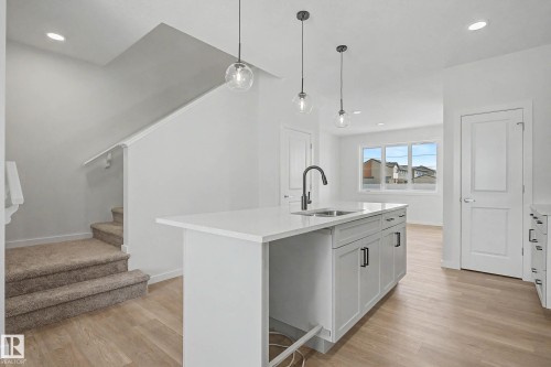 Kitchen island featuring an undermount sink, matte black faucet, and pendant lighting - 720 Southfork Drive, Leduc, AB - Indoor Photo Showing Kitchen With Upgraded Kitchen
