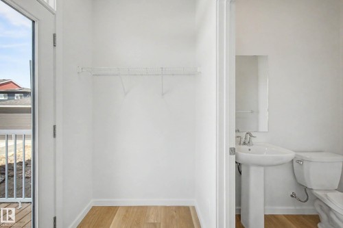 Unfinished closet space featuring a wire shelving unit, wood-finish flooring, and a glass-paneled door - 720 Southfork Drive, Leduc, AB - Indoor Photo Showing Bathroom