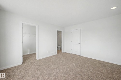 Carpeted room featuring white walls, a white interior door with a silver handle, and an open doorway revealing a closet with wire shelving - 720 Southfork Drive, Leduc, AB - Indoor Photo Showing Other Room