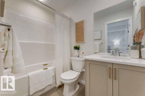 Bathroom featuring a white integrated tub and shower unit, a toilet, and a vanity with a white countertop and light-toned cabinetry - 720 Southfork Drive, Leduc, AB - Indoor Photo Showing Bathroom