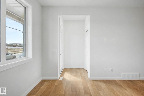 Bright interior space featuring wood-finish flooring, white walls, and a large multi-pane window - 720 Southfork Drive, Leduc, AB - Indoor Photo Showing Other Room