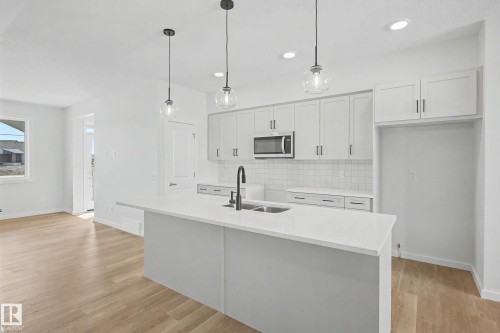 Modern kitchen featuring white shaker cabinetry, stainless steel microwave, and white subway tile backsplash - 720 Southfork Drive, Leduc, AB - Indoor Photo Showing Kitchen With Double Sink With Upgraded Kitchen