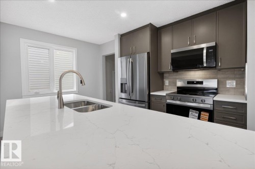 Kitchen featuring a large central island with a double stainless steel sink and a gooseneck faucet - 9723 65 Avenue, Edmonton, AB - Indoor Photo Showing Kitchen With Double Sink With Upgraded Kitchen
