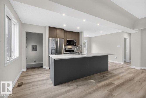 Modern kitchen featuring a central island with an integrated sink and gooseneck faucet - 9723 65 Avenue, Edmonton, AB - Indoor Photo Showing Kitchen