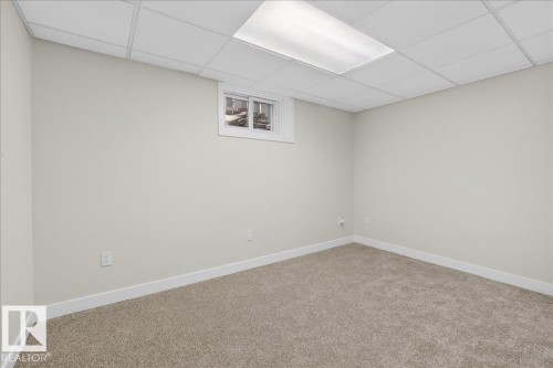 Room with light-colored walls, neutral carpet flooring, a drop ceiling, and a single window with white trim - 9723 65 Avenue, Edmonton, AB - Indoor Photo Showing Other Room