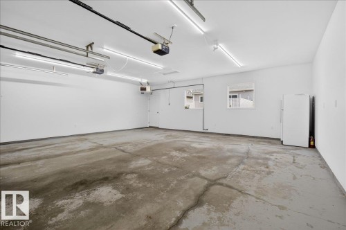 Spacious garage featuring a concrete floor, white painted walls, and multiple ceiling-mounted fluorescent light fixtures - 9723 65 Avenue, Edmonton, AB - Indoor Photo Showing Garage