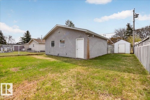Detached garage featuring a stucco exterior, a white entry door, two windows, and an adjacent storage shed - 9723 65 Avenue, Edmonton, AB - Outdoor