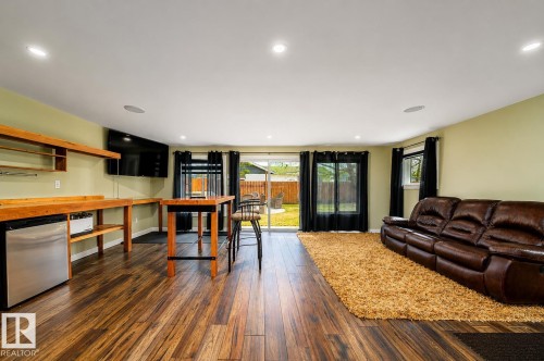 Spacious entertainment area featuring wood-finish flooring, recessed lighting, and a built-in wet bar with a stainless steel mini-refrigerator - 126 Harrison Drive, Edmonton, AB - Indoor