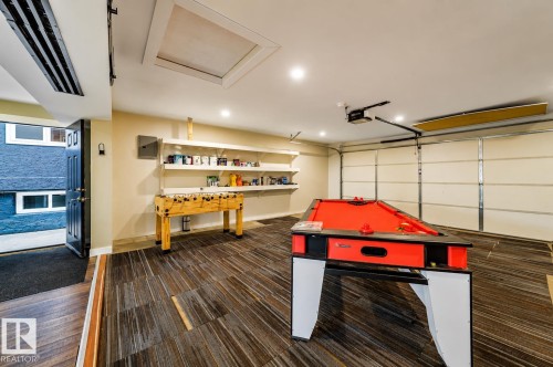 Finished basement area featuring recessed lighting, multi-tone wood-finish flooring, and a garage door - 126 Harrison Drive, Edmonton, AB - Indoor Photo Showing Other Room