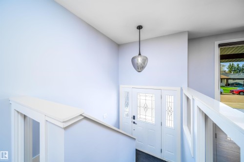 Entryway featuring a white door with decorative glass inserts, sidelight windows, and a contemporary pendant light fixture - 126 Harrison Drive, Edmonton, AB - Indoor Photo Showing Other Room