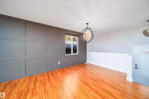 Expansive room with wood-finish flooring, a feature wall with board and batten paneling, and a large window - 126 Harrison Drive, Edmonton, AB - Indoor Photo Showing Other Room