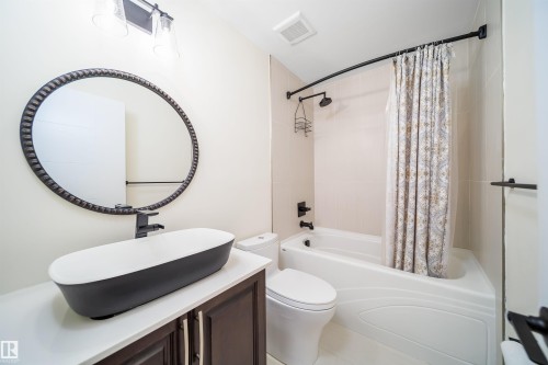 Modern bathroom featuring a vessel sink, dark wood-finish vanity, and a tub-shower combination with tiled surround - 126 Harrison Drive, Edmonton, AB - Indoor Photo Showing Bathroom